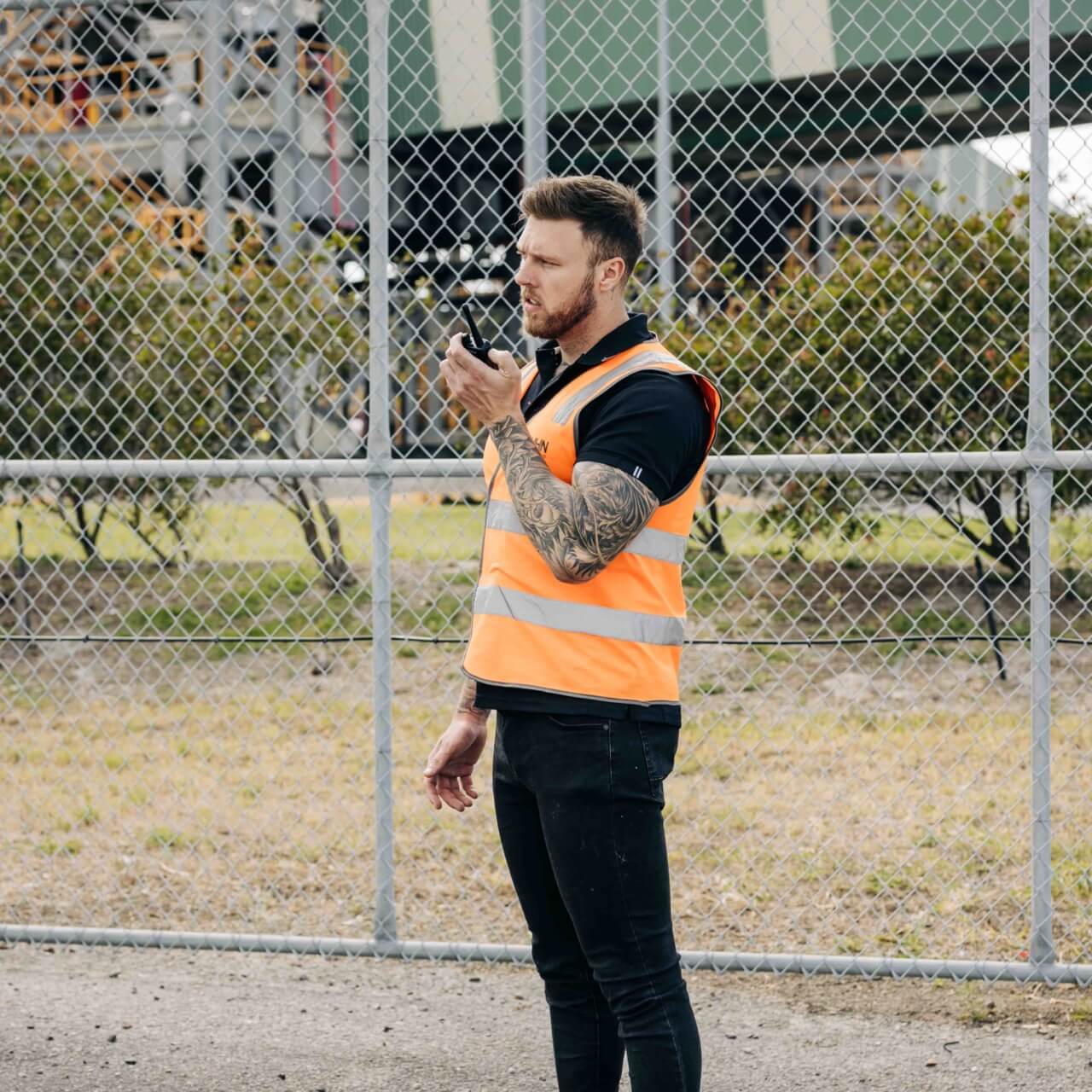 NHN employee speaking on a handheld radio outside a facility