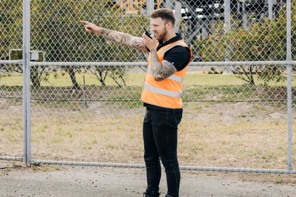 Security guard speaking into a radio and pointing into the distance
